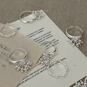 Detailed view of silver rings with bead fringes and minimalist balls on linen fabric