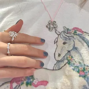 Detailed view of elegant silver floral jewelry set with necklace and two rings on model