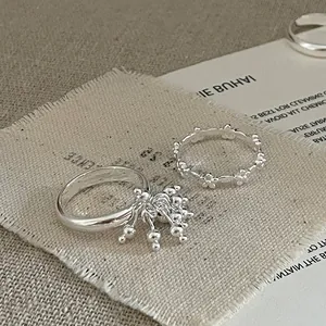 Close-up of silver ring set featuring a fringe tassel bead and cutout flower wreath band