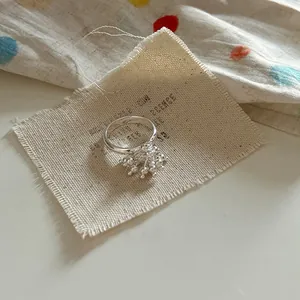 Macro shot of silver fireworks floral ring on textured beige canvas fabric