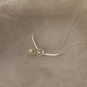 Dettaglio del ciondolo a nodo in metallo argento con perla d'acqua dolce bianca su catenina