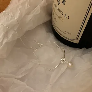 Dettaglio della collana argentata a nodo con ciondolo in perla d'acqua dolce su carta