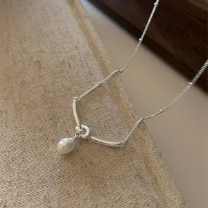 Dettaglio del ciondolo in metallo annodato argento con perla d'acqua dolce su catenina