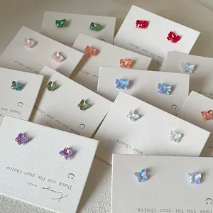 Makroaufnahme bunter Schmetterling-Ohrstecker-Sets auf weißen Displaykarten