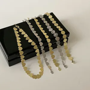 Vista detallada de collares de discos redondos y de corazón en oro y plata con cierres de mosquetón