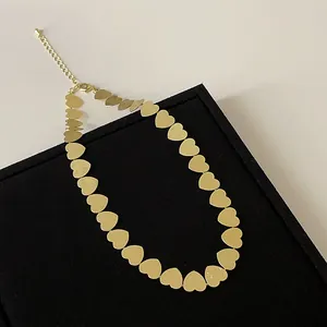 Detalle del collar de corazón dorado que muestra la textura de metal cepillado fino