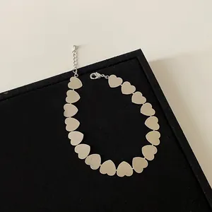 Detalle de los dijes de corazón de metal cepillado y cierre ajustable en el brazalete