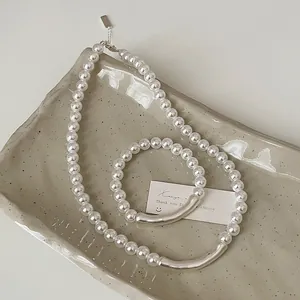 Details von matten Silberrohren und weißen Perlen an Halskette und Armband-Set