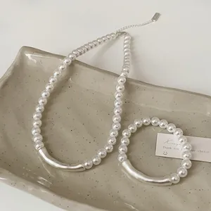 Detailansicht eines Perlen-Schmucksets mit Silberröhren auf einem Keramikteller