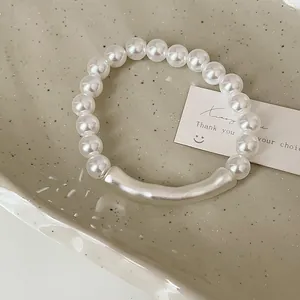 Detailansicht eines Perlenarmbands mit silbernem Röhrchen auf einer Keramikschale