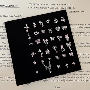 Detail view of pink zircon stud earrings with heart and bow motifs on black velvet pad