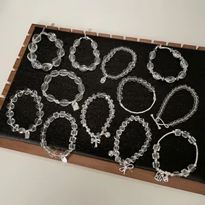 Elegante klare Kristallperlenarmbänder mit Silberanhängern auf schwarzem Samttablett