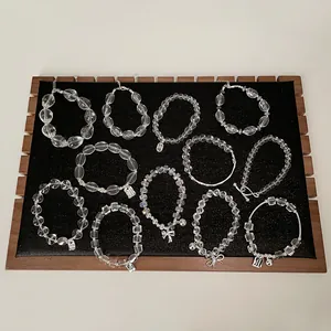 Detaillierte Sammlung klarer Kristallarmbänder mit Silberanhängern auf schwarzem Samt