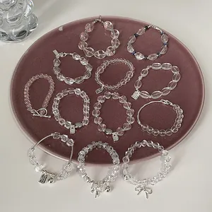 Elegantes Armband-Set aus klaren Kristallperlen mit Silberanhängern auf dem Teller