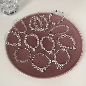Details von zehn minimalistischen Kristallperlen-Armbändern mit silbernen Anhängern im Teller