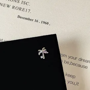Detailed macro view of a silver palm tree stud earring with purple zircon and white crystals