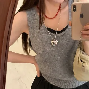 Collier à grand pendentif cœur argenté superposé à une chaîne de perles rouges sur pull