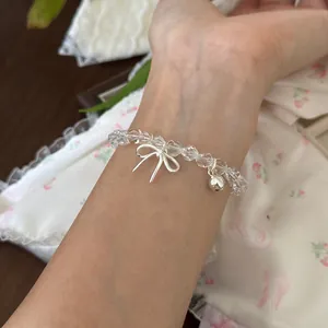 Detailaufnahme von klarem Kristallperlenarmband mit silbernem Schleifenanhänger am Handgelenk