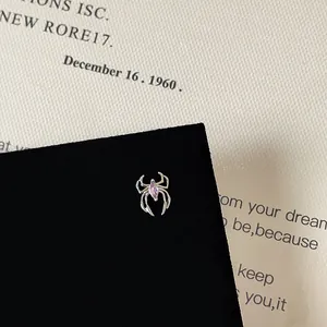 Detailed macro view of silver spider earring with pink zircon on black display card
