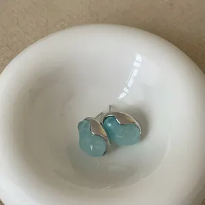 Dettaglio di orecchini a camelia azzurri con cornice in metallo argentato lucido
