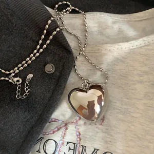 Détail d'un pendentif cœur poli avec une chaîne à billes et un fermoir mousqueton robuste