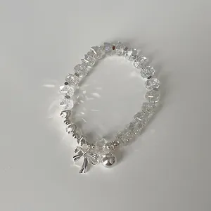 Detail eines Perlenarmbands mit klaren facettierten Kristallen und Schleifenanhänger