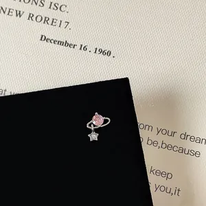 Macro view of silver star planet stud earring featuring a pink zircon and small star charm
