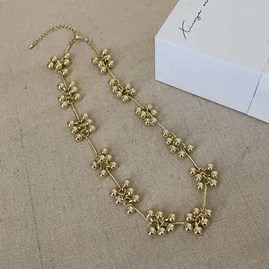 Detailaufnahme der goldenen Perlenkette mit Kugelclustern auf Leinenstoff