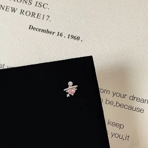 Close-up of Saturn planet stud earrings with pink cubic zirconia on black velvet card