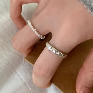 Dettaglio di anello a stella vintage in argento e anello di perle elegante indossati insieme