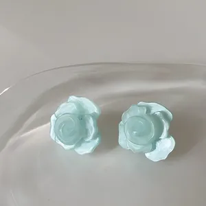 Primo piano di orecchini a perno a camelia blu menta traslucidi con finitura perlata