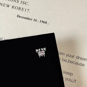 Detailed close-up of a silver butterfly earring featuring pink zircon and white crystals