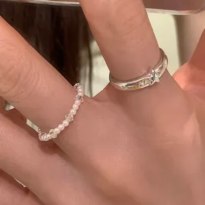 Dettaglio dell'anello di perle e dell'anello d'argento con stella incisa sul dito