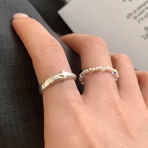 Dettaglio del set di anelli a strati con stella in argento goffrato e perle delicate