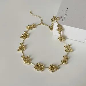 Nahaufnahme der goldenen Perlenblumen und des Karabinerverschlusses der Halskette
