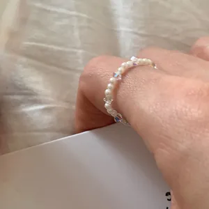 Dettaglio di un anello di perle con perline bianche e perline sfaccettate iridescenti