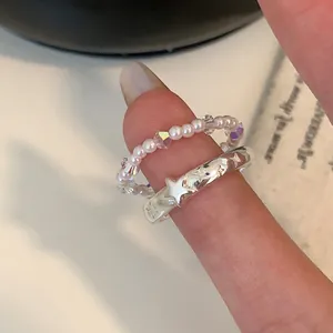 Dettaglio dell'anello di perle e fascia d'argento con stelle su una mano
