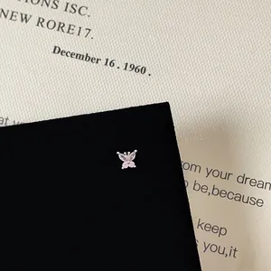 Macro shot of a silver butterfly stud earring with pink zircon stones on black velvet