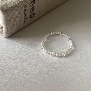 Dettaglio di un elegante anello con perle bianche e cristalli trasparenti su libro