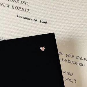 Macro shot of pink heart zircon stud earring with screw back on vintage paper background