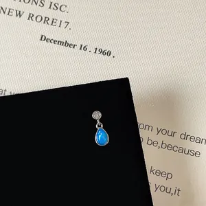 Detailed macro view of silver screw back earring with blue opal and sparkling zircon stud
