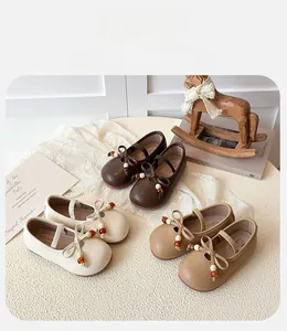 Detailed view of girls bow Mary Jane shoes in three vintage colors on a warm decorative setting