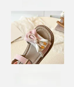 Detailed macro view of pink and white girl's sandals featuring a decorative bow and gold metal buckle