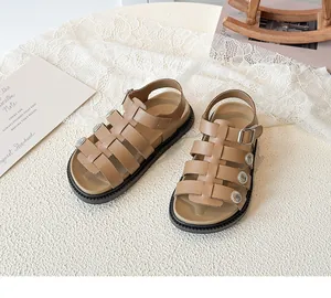 Detailed view of brown retro girls sandals with metal buckles and non-slip thick black soles