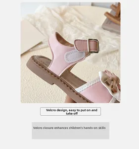 Detail of pink girls' sandals with velcro strap and white bow with golden hardware