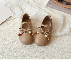 Detail view of khaki Mary Jane shoes for girls with beaded bow and leather texture