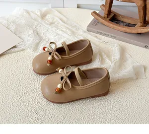 Detailed view of girls' brown Mary Jane shoes with bow and vintage beads on soft lace