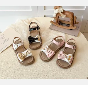 Top view of four girls' sandals with bow details and adjustable straps on a vintage table