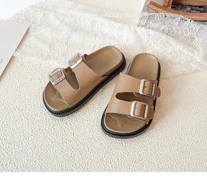 Detail view of children's brown double-strap sandals with metallic adjustable buckles