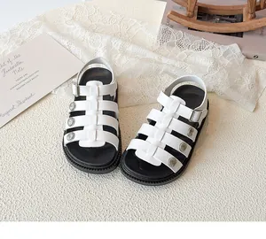 Detail of girls' white woven sandals with vintage silver buckles and a thick black sole